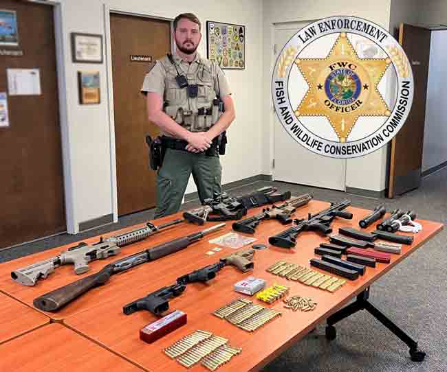 Florida Fish and Wildlife Conservation Commission officer standing behind tale with firearms, clips, and ammunition displayed