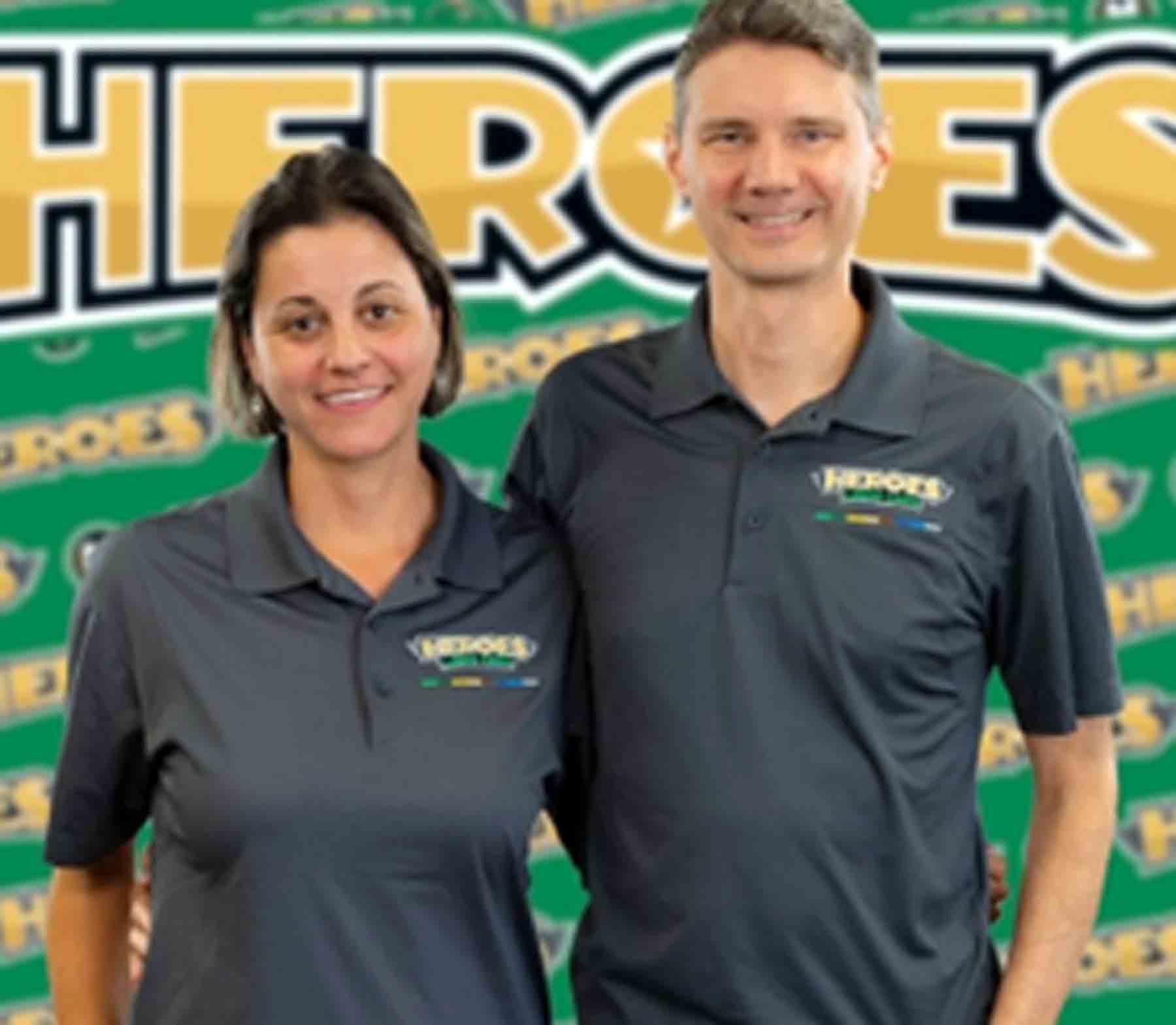 Brad and Fernanda Buinicky are standing together with Heroes Lawn Care signage in the background.