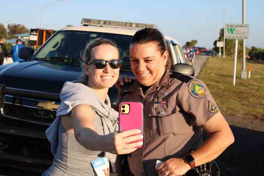 A female race participant takes a selfie with FHP Trooper Toni Schuck
