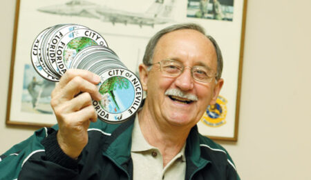 Randall Wise at his desk holding City of Niceville decals