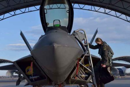 U.S. Air Force Maj. Nichole “Vapor” Ayers removes a cover from the cockpit of an F-22