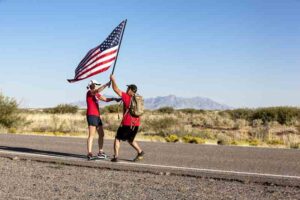 Team Red, White & Blue members pass an American Flag during Old Glory Relay
