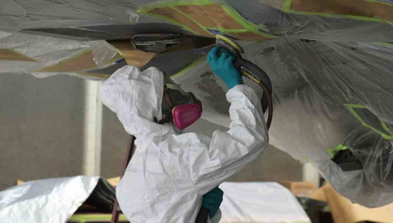 U.S. Air Force Staff Sgt. August Hoffman, 325th Maintenance Squadron low observable craftsman, sands off paint from an F-22 Raptor