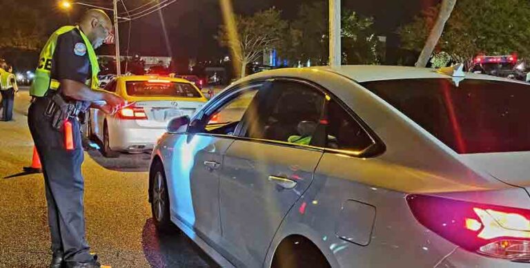 safety checkpoint over the Labor Day weekend in Fort Walton Beach Florida at night; officer checking registration, driver license standing next to vehicle