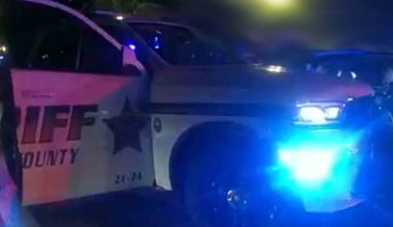 Okaloosa County Sheriff's Office patrol vehicle at night, on scene, open door, with blue lights