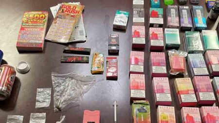 lottery tickets, vape pens, drugs, syringe, fake cans with open hidden compartments on table