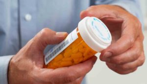 hands holding prescription drug container