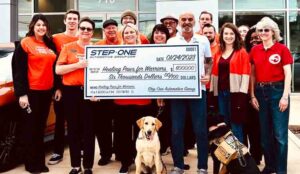 Group photo with service dogs, people holding large, ceremonial check