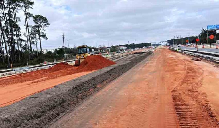 Road base construction with heavy equipment spreading red clay