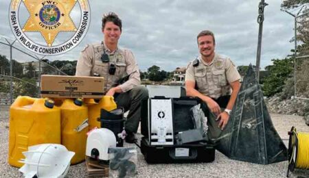 Two Florida Fish and Wildlife Conservation Commission officers on land with recovered stolen marine equipment and supplies