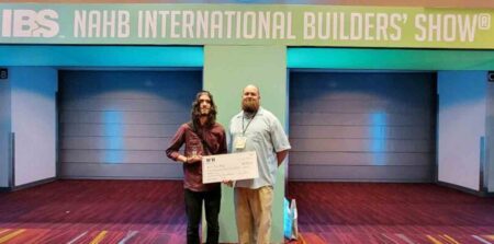Troy Young and his building trades teacher, Danny Meinecke, displaying a poster-sized scholarship check.