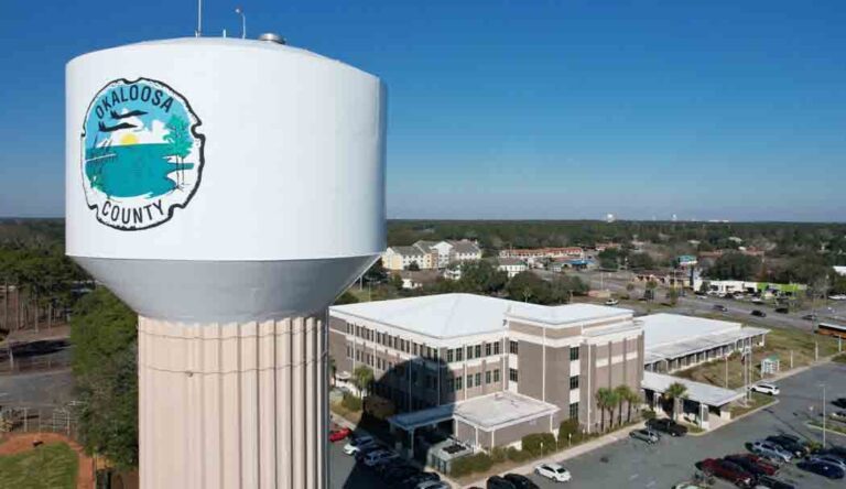 Okaloosa County Administration Building in Shalimar, aerial view, with a water tower with county logo in foreground on the left
