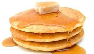 stack of three pancakes with syrup, pat on butter on top