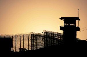 prison tower, fence topped with barbed wire, at sunset