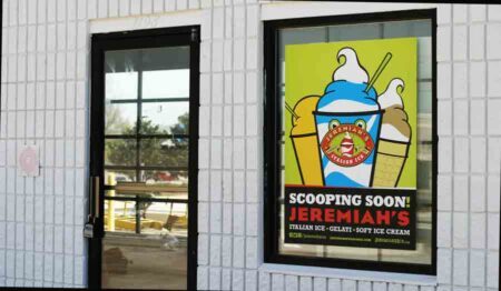 Front entrance (under construction) of Jeremiah's Italian Ice in Niceville with poster in the window reading. SCOOPING SCOON!