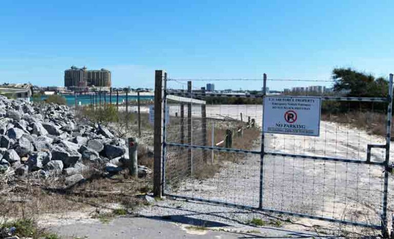 A closed gate at the entrance to the parking area at the East Pass Beach with a sign reading "No Parking."
