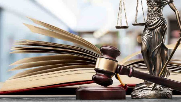 Open law book, gavel, scales of justice in library