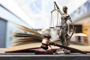 Open law book, gavel, scales of justice in library