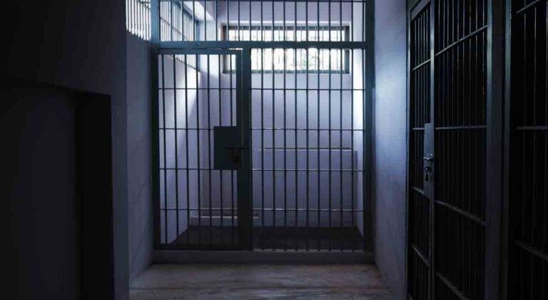 prison cells, one centered in hallway, lighted, and a dark cell on the right