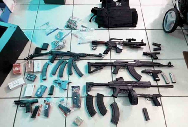 nine firearms, hundreds of rounds of ammunition and a ballistic vest displayed on the floor