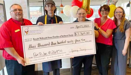 Five Costa McDonald's employees standing with poster-sized check.