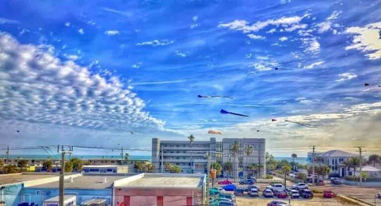 Scene from the Cocoa Beach Kite & Beach Fest with kites flying, buildings and beach in the background