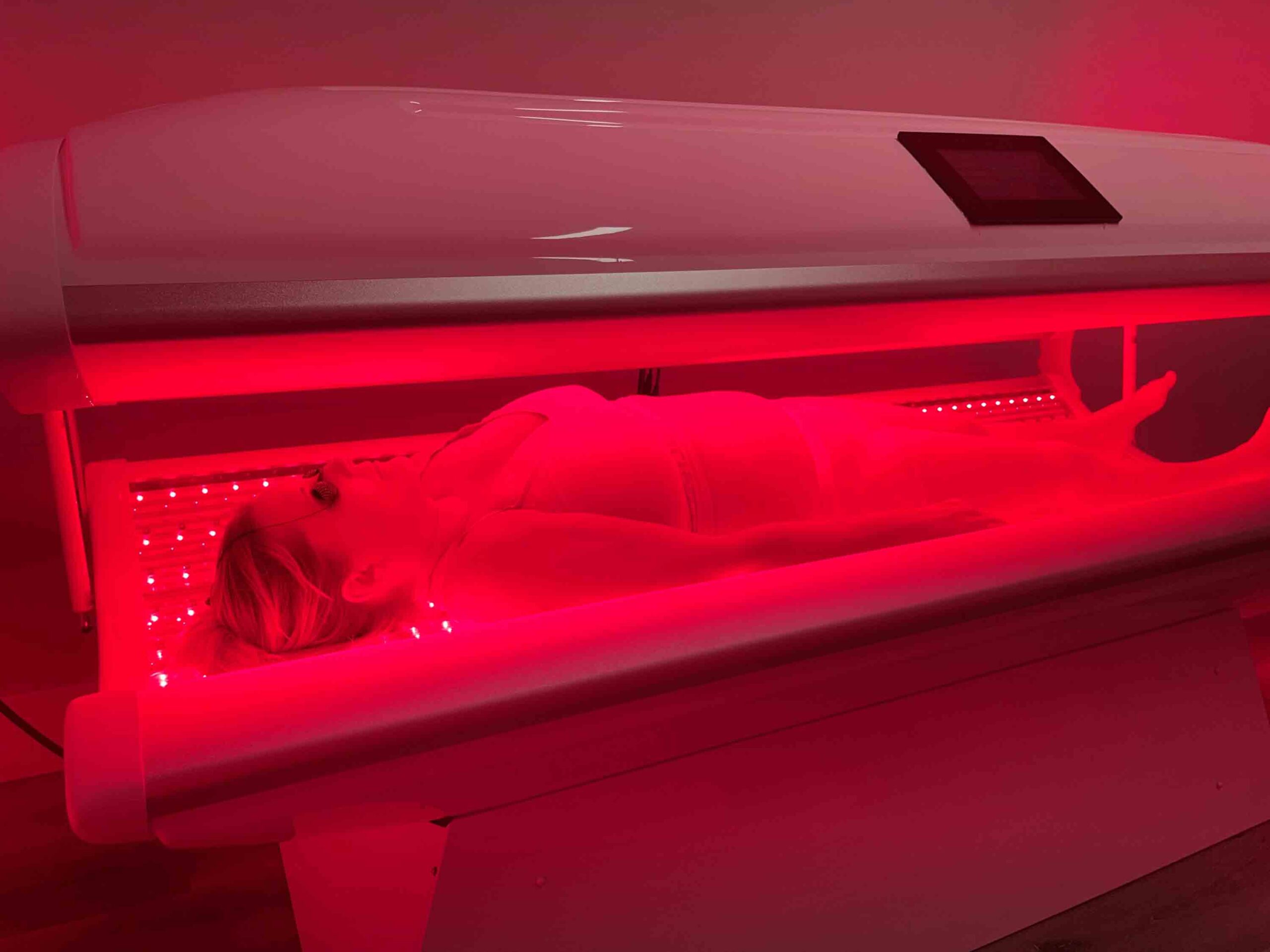 Woman in red light therapy whole-body bed