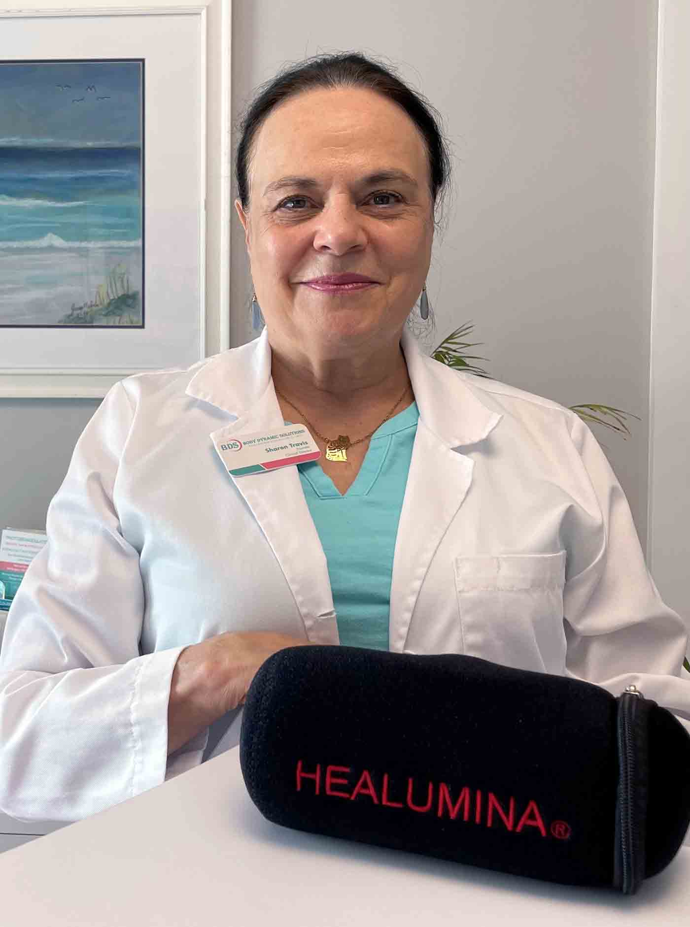 Sharon Travis standing next to counter with HEALUMINA device in black zippered bag.