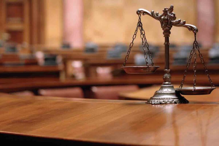 Scales of Justice on a table in empty courtroom