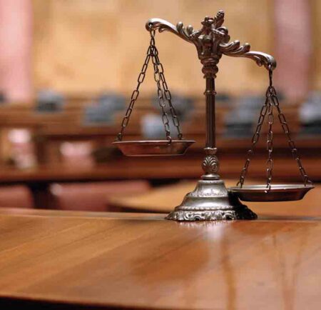 Scales of Justice on a table in empty courtroom