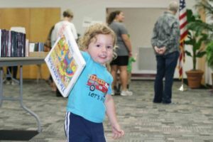 Young boy holding a children's science book at the book sale event