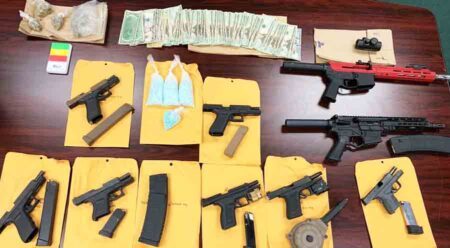 handguns, rifles, cash, drugs displayed on table