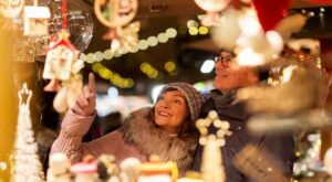 happy senior couple at outdoor christmas market shopping after dark