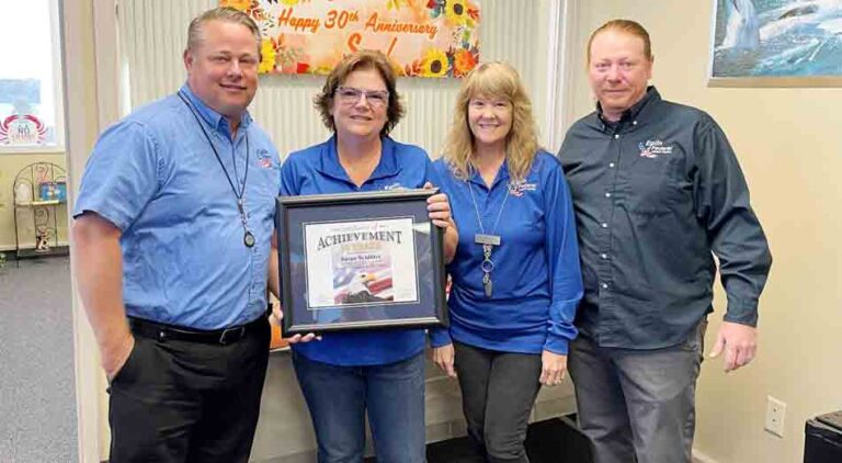EFCU Information Systems ATM/ITM Supervisor Sue Schlitter holding framed achievement certificate and standing with three other employees