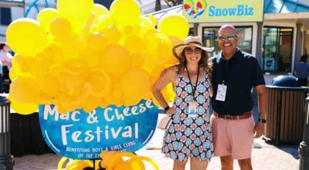 Man and woman posing next to Mac & Cheese Festival sign