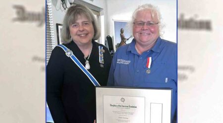 two women standing side-by-side, one holding a framed certificate