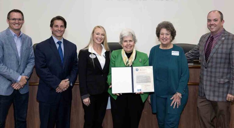 six people standing side-by-side, one displaying a proclamation