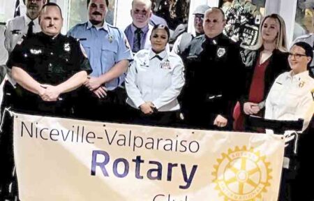large group of 2023 first responder award-winners in uniform standing behind a Rotary Club banner in Niceville, Florida