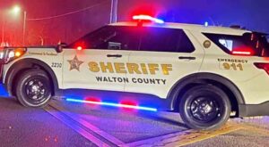 A Walton County Sheriff's Office patrol vehicle stopped in the street with red and blue lights flashing during the night
