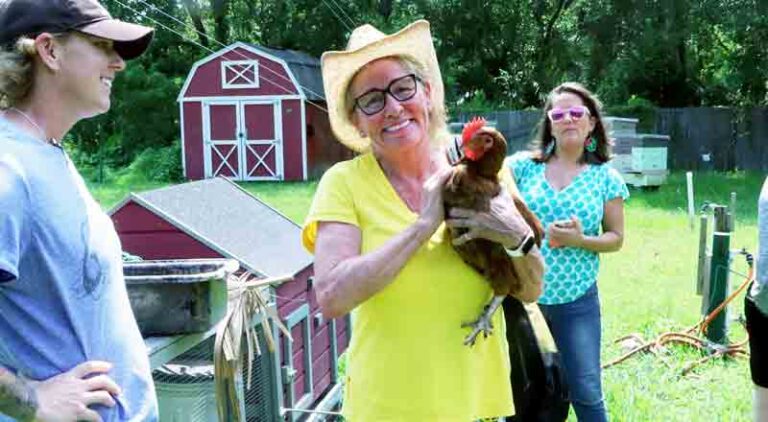 woman holding a chicken while two other people look on