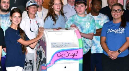 Rocky Bayou Christian School students are standing next to a former mail collection box they painted for use as a drug-takeback program collection box at the Niceville Police Department. "Got Drugs?" is painted on the front.