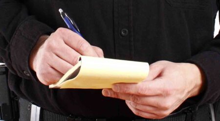 close up of police officers hands while writing a ticket