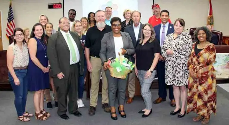 Michelle Robinson Cook holding gift basket with family, friends and school officials at Okaloosa County School Board meeting