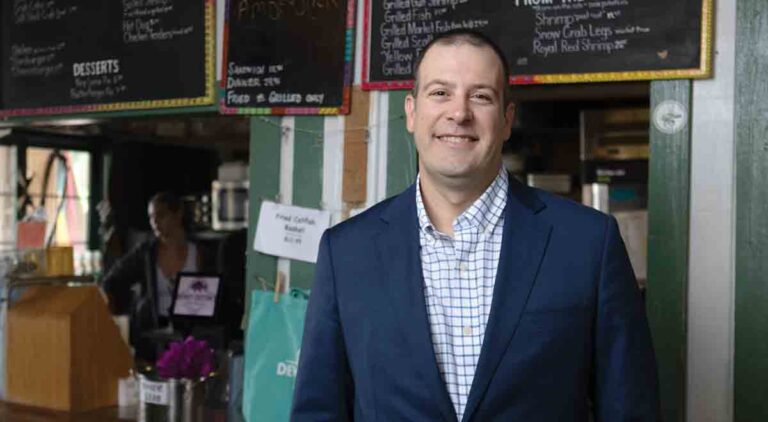 Parker Destin in a blue sport jacket standing in his restaurant, Dewey's Seafood