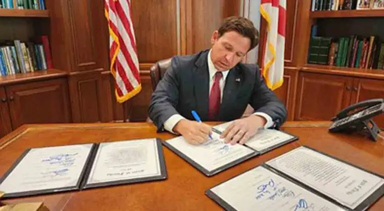 Florida Governor Ron DeSantis at his desk signing a bill.