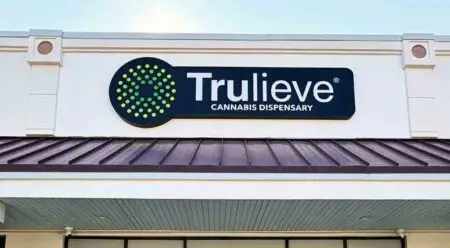 Trulieve Cannabis Dispensary sign on building above awning in daylight.