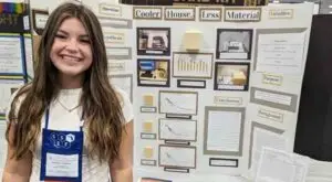 Emmalyn Otzenberger of the Okaloosa STEMM Academy standing in front of her science project display, cooler house, less material.