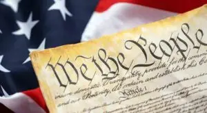 Preamble to the Constitution of the United States and American Flag. Old yellow paper with We The People text