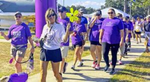 A line of people, most in purple t-shirts, walking in the 2024 Walk to End Alzheimer’s at the Air Force Armament Museum in Okaloosa County, Fla.