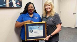 Eglin Federal Credit Union Human Resources Supervisor Robin Lakes holding framed certificate of achievement with SVP/Chief HR Officer Gina Denny